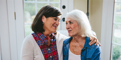 Younger and older woman smiling affectionately at one another